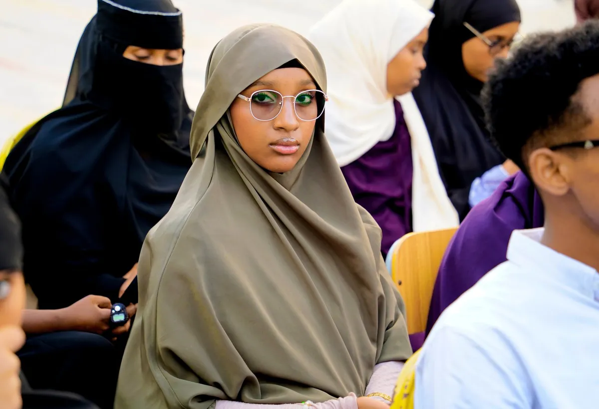 A young woman seated among participants at an IMPACTSOM event