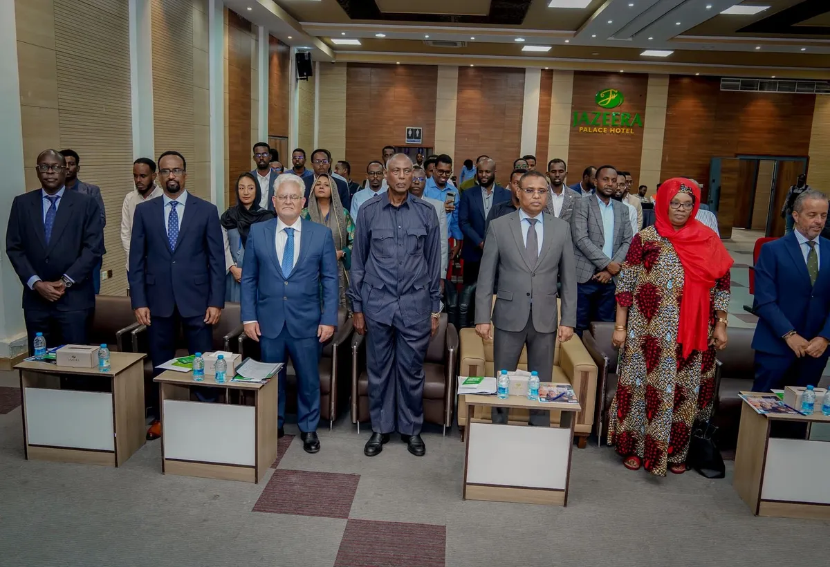 Officials signing a partnership agreement at a formal ceremony, with colleagues standing behind them