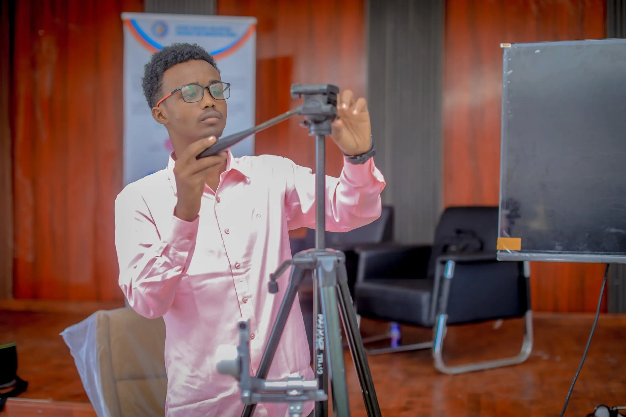 A videographer adjusting a tripod at an indoor event